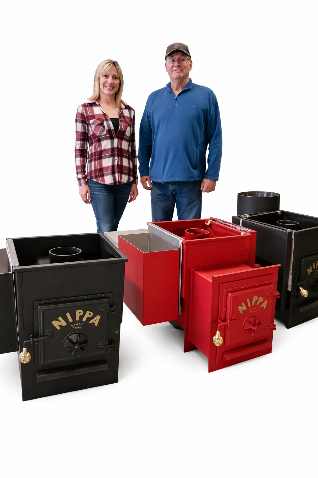 Former Nippa Sauna Stove owner Dean Michael with his daughter Diane standing behind a collection of black and red Nippa wood burning sauna stoves in Beulah Michigan